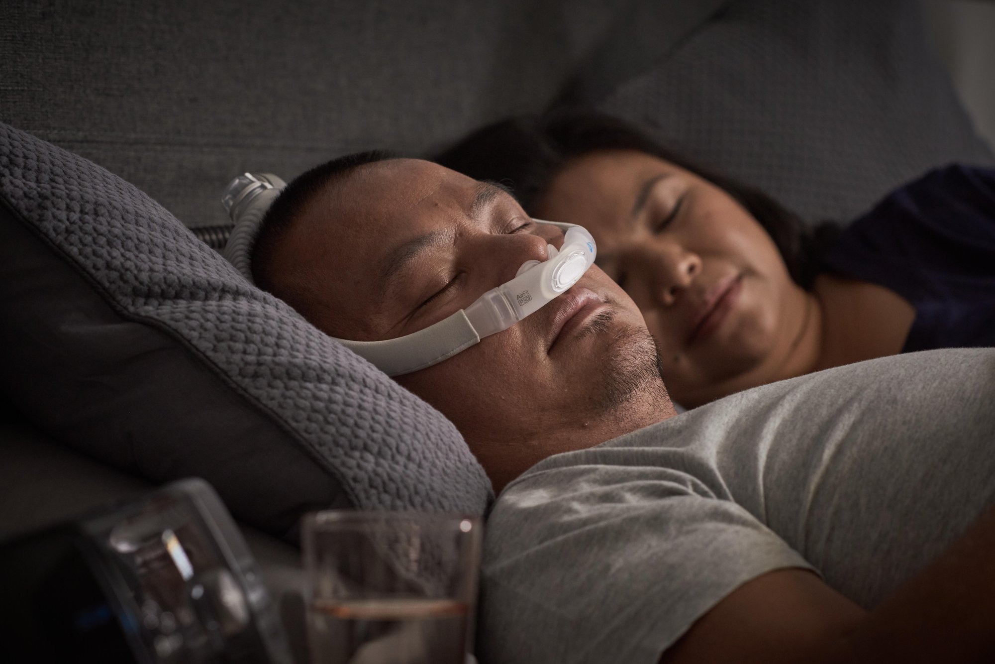 Man and Woman sleeping next to each other, man is using a cpap mask.