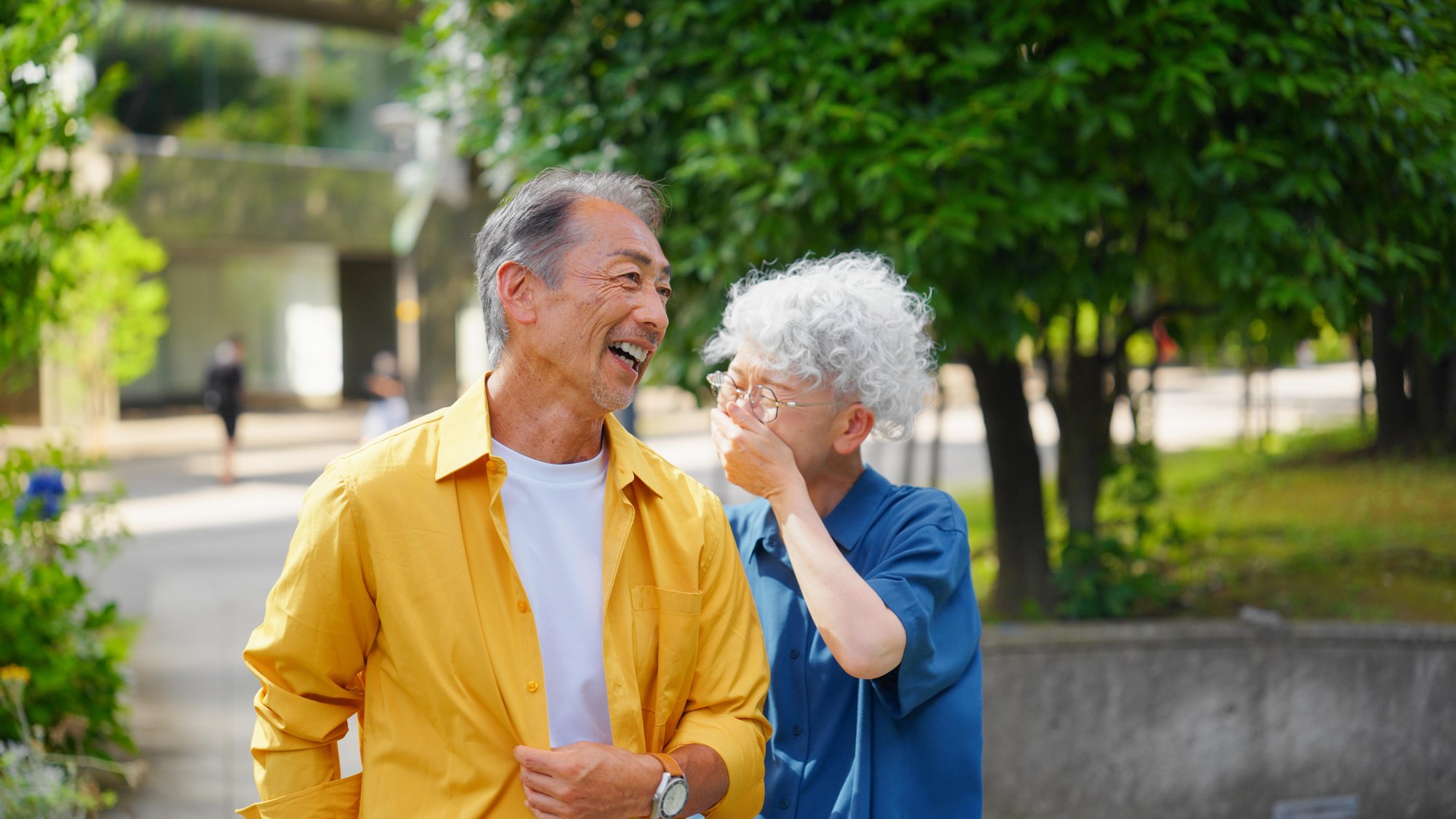 Elderly couple walking in park, smiling and laughing
