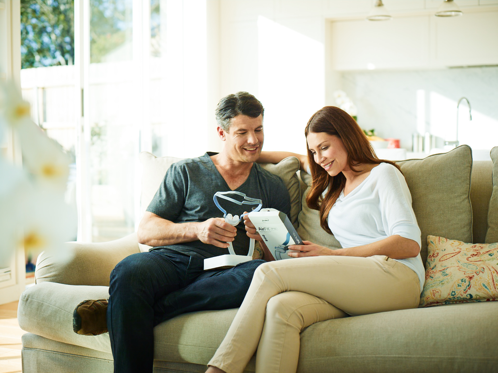 Man and woman on couch, inspecting their new CPAP mask