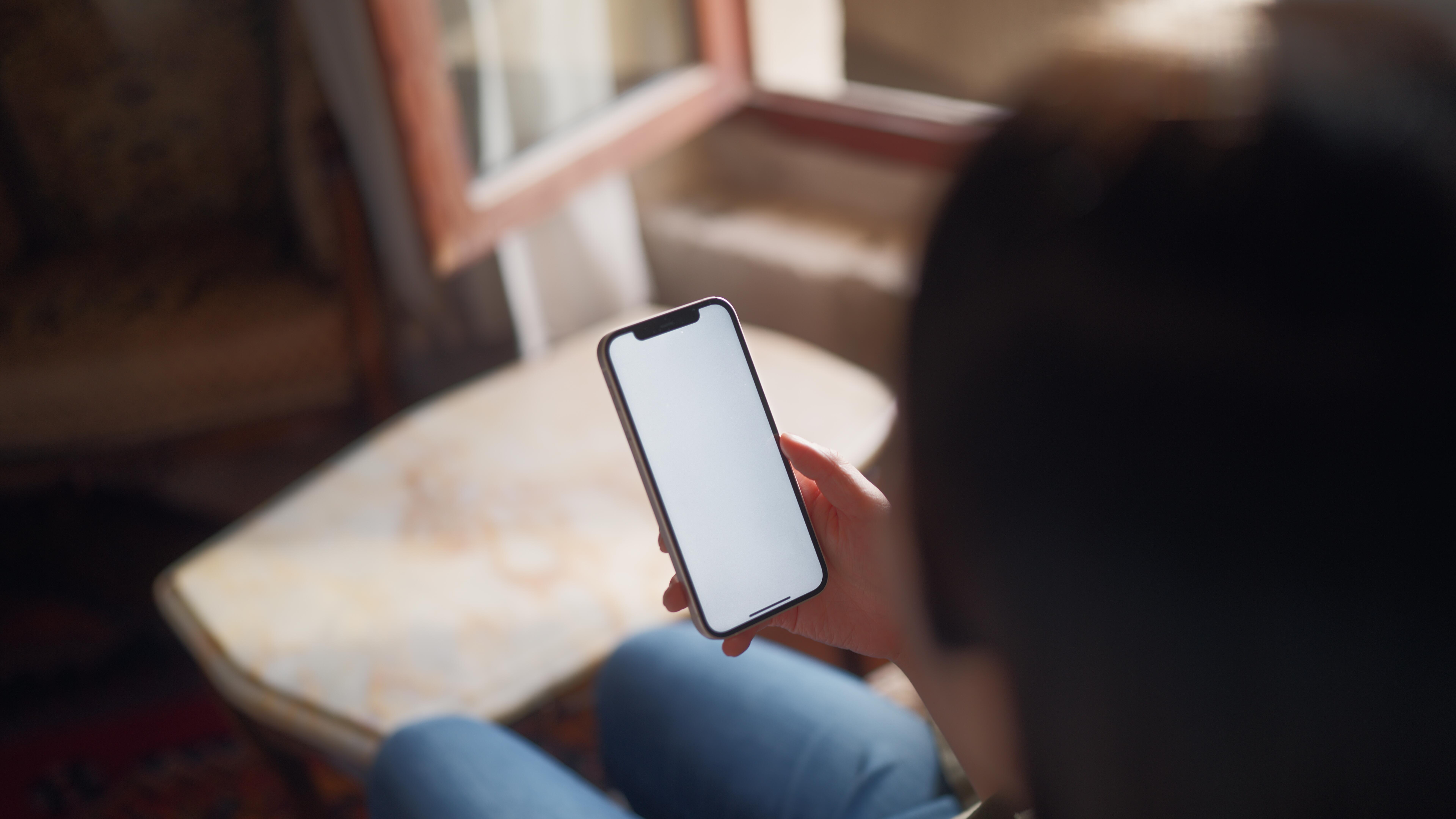 Young female tourist relaxing and using her smart phone in hotel room