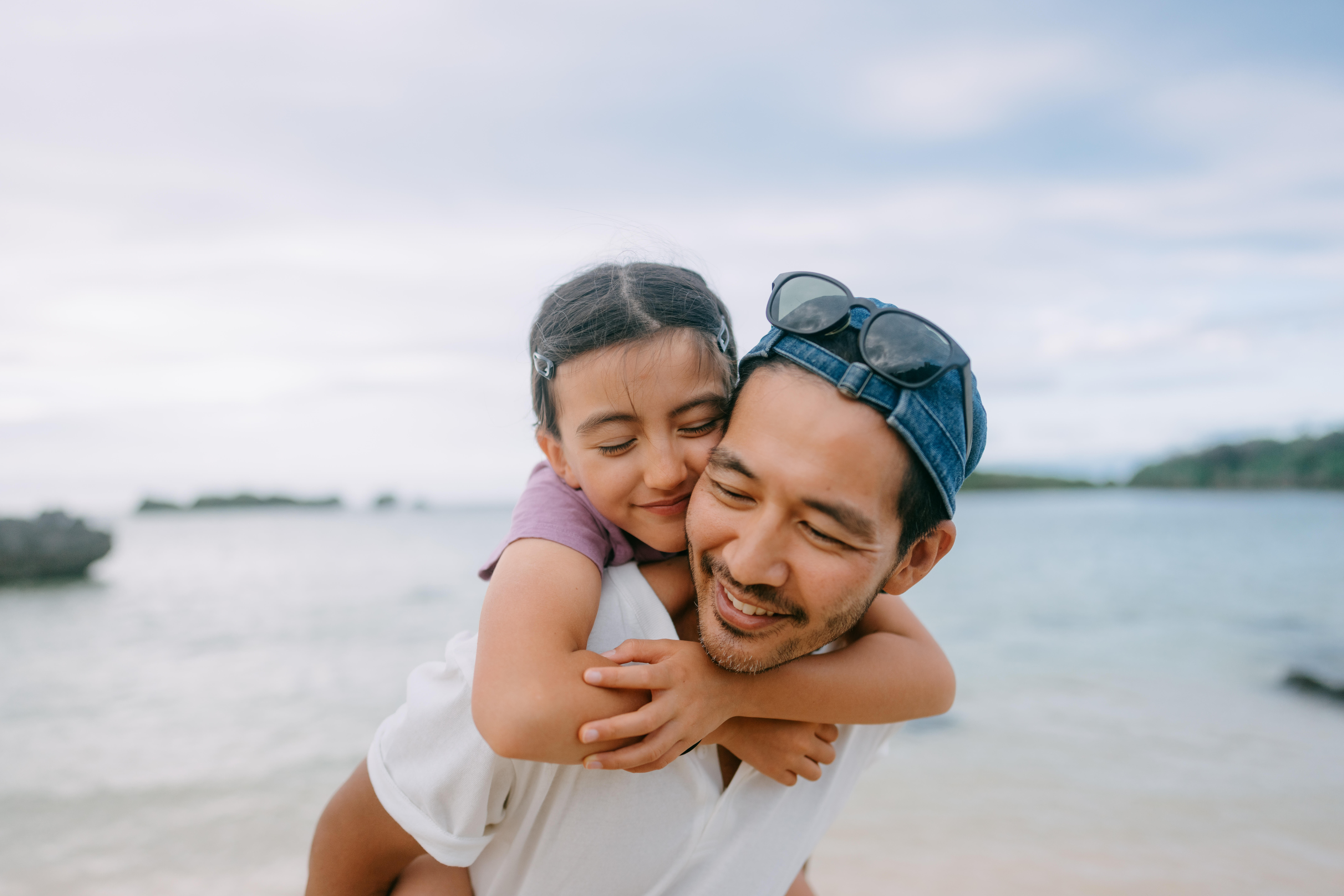 Father giving piggyback ride to young daughter on beach