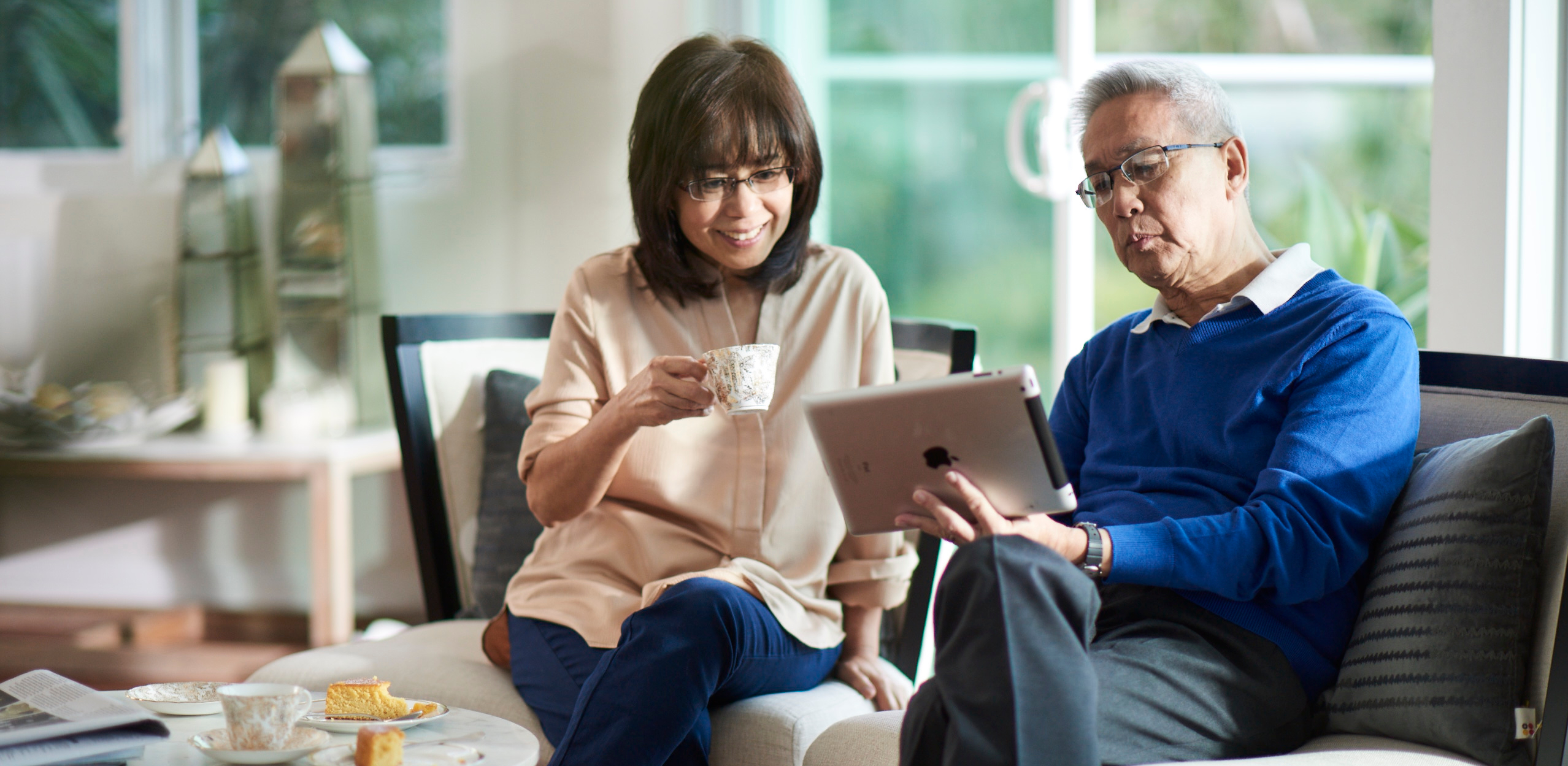 Man and woman on the couch, looking at iPad.